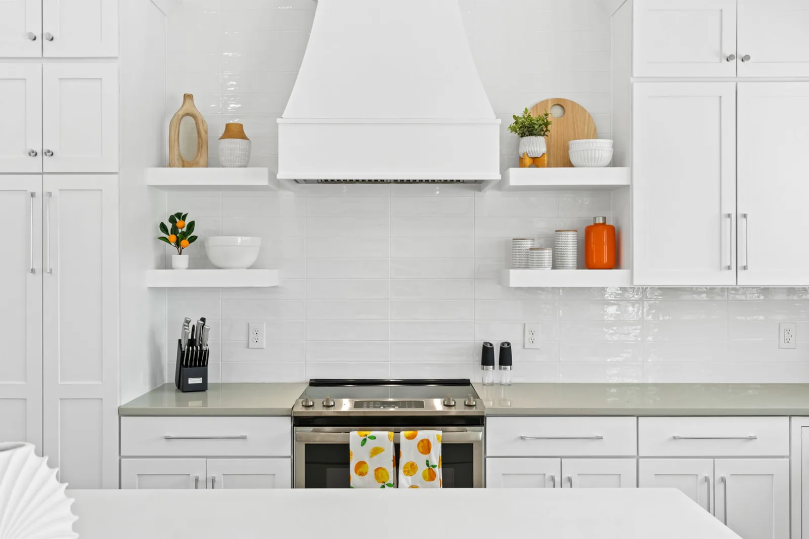 Bright white coastal kitchen with range hood and open shelving