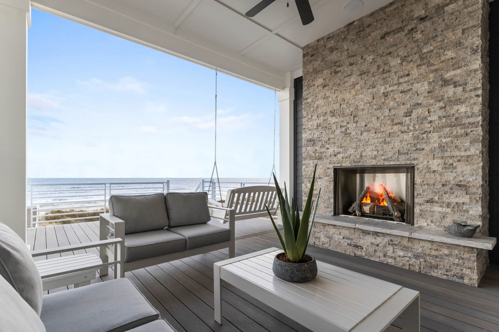 Covered oceanfront porch with stone fireplace, seating, and ocean views
